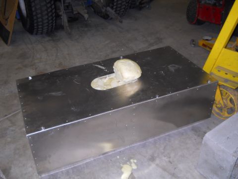 1992 Ford Bronco - A metal box with a hole and a beige object sits on a concrete floor, with various equipment visible in the background.
