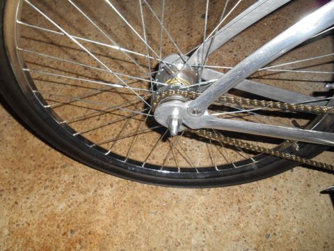 Silver bicycle rear wheel with gold chain and spokes
