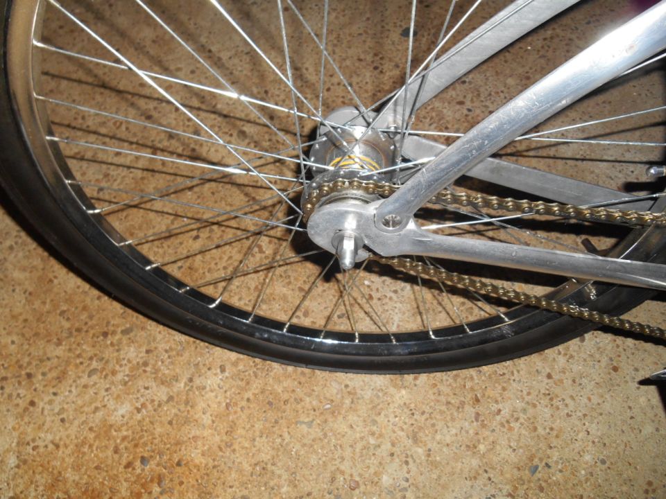 Silver bicycle rear wheel with gold chain and spokes
