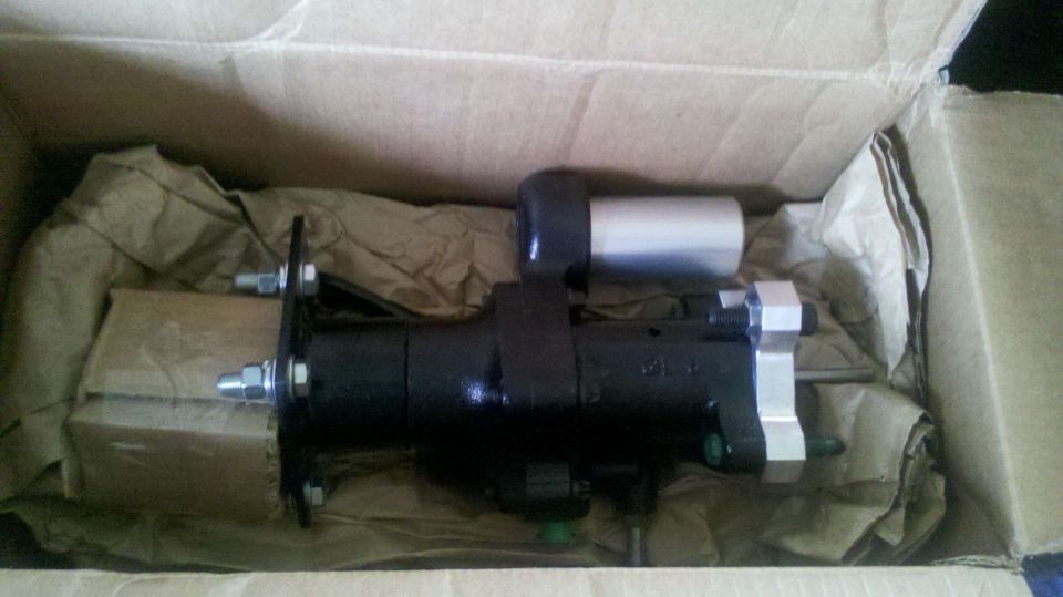 Black automotive part in a cardboard box with brown paper packing