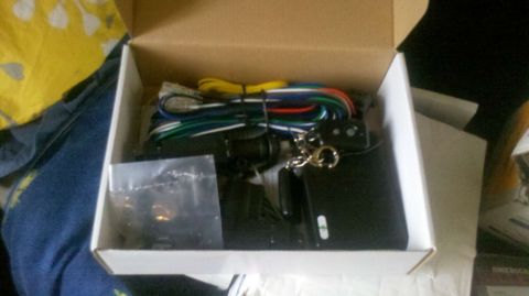 1982 Ford Bronco - Car alarm system components are laid out in a cardboard box, ready for installation.