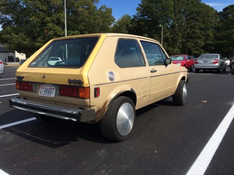 1983 Volkswagen Rabbit - Rear view of a tan 1983 Volkswagen Rabbit hatchback with aftermarket hubcaps.