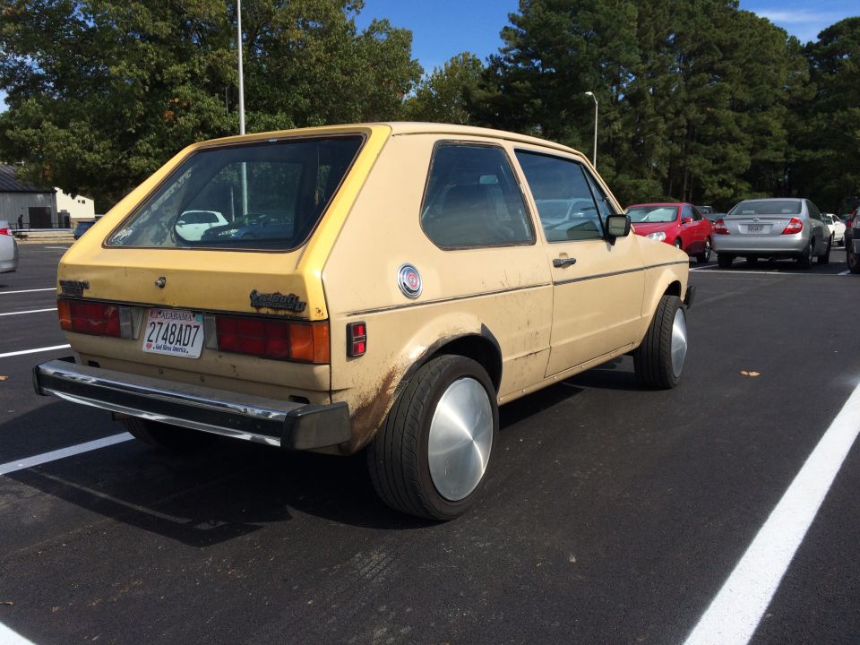 Tan 1983 Volkswagen Rabbit hatchback parked in a lot, showing rear quarter view. License plate 2748AD7