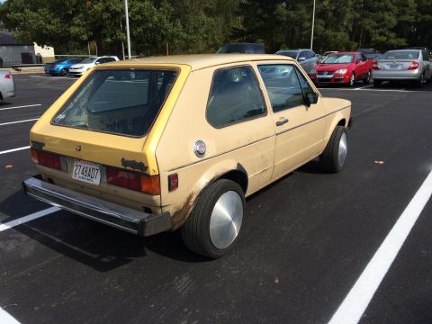1983 Volkswagen Rabbit - A tan 1983 Volkswagen Rabbit is parked in a lot, showing its rear and side profile.