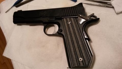 1979 Ford Bronco - A close-up view of a black pistol with custom grips, resting on a white cloth with tools nearby.