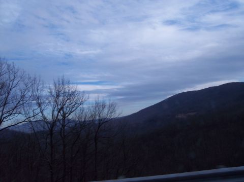 1990 Ford Bronco - A cloudy sky looms over a mountainous landscape with silhouetted trees in the foreground.