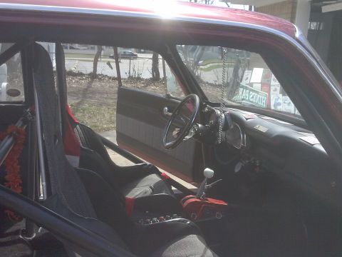 1960 Ford Falcon - The interior of a red car is shown with racing seats, a roll cage, and a prominent shifter.