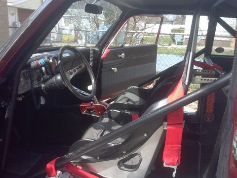 1960 Ford Falcon - The interior of a modified vehicle features a roll cage, racing seats, and aftermarket gauges, suggesting a performance-oriented build.