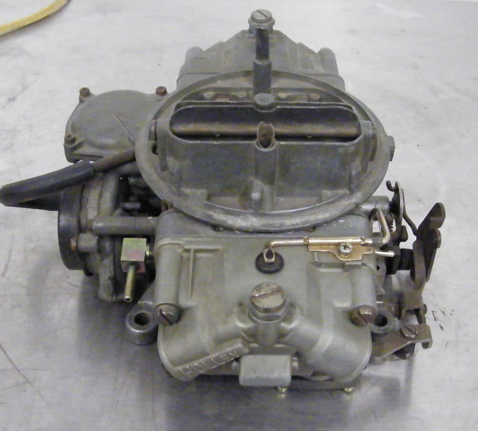 Carburetor with metal casing and various linkages, viewed from the front