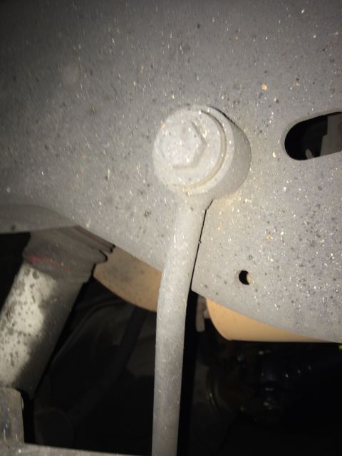 1990 Ford Bronco - A close-up view of a vehicle's suspension linkage, showing a dusty metal component and a bolt head.