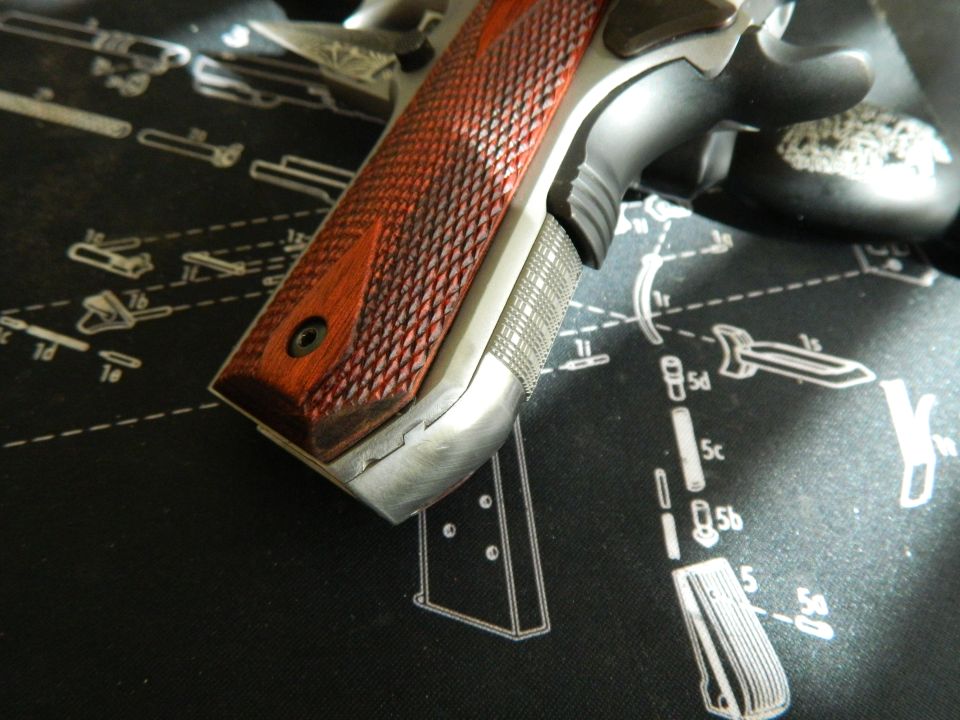 Pistol grip with wood paneling and silver frame on a black mat with gun diagrams