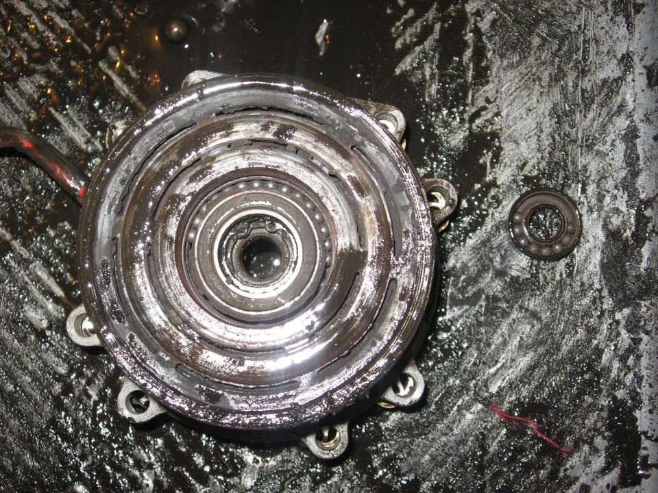 Disassembled compressor clutch assembly with bearing on a dirty surface