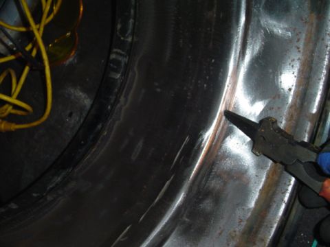 1993 Ford Bronco - Close-up of a vehicle's wheel well interior, showing wires and pliers in use.