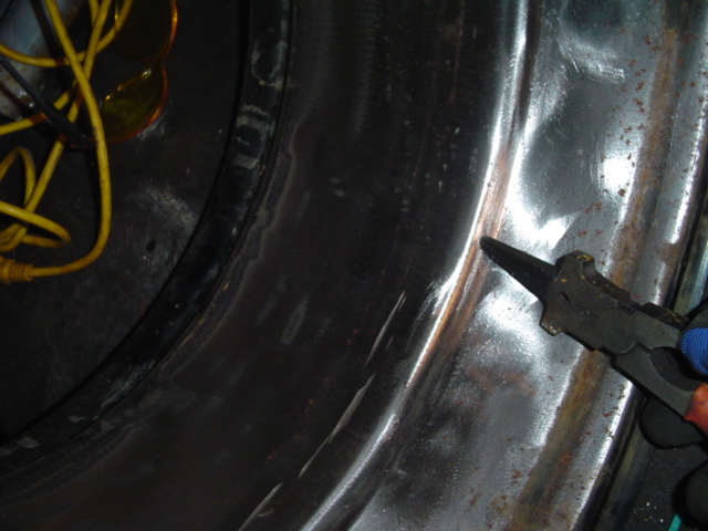 Interior of a wheel well with yellow wires and pliers being used