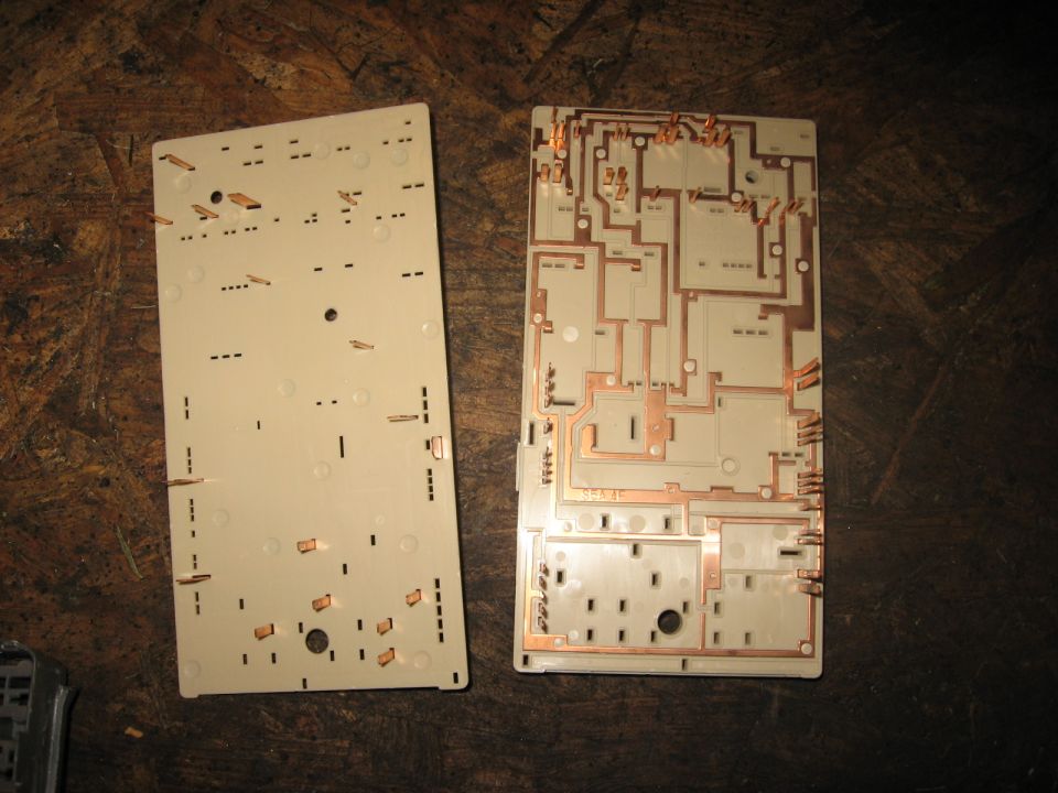 Two white plastic fuse box components with copper circuitry visible on one