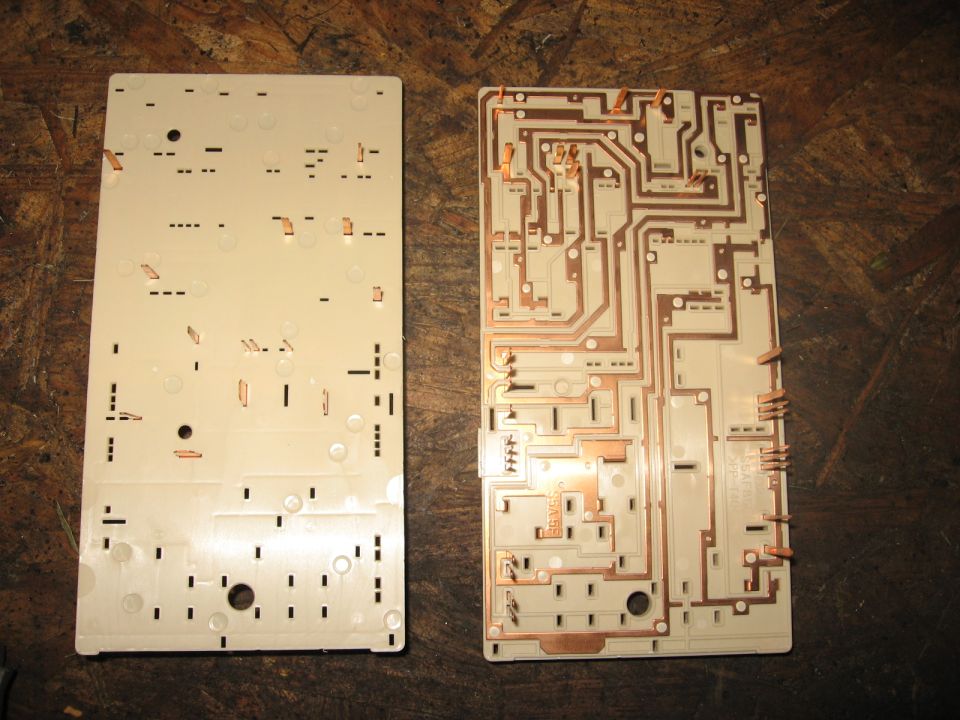 Two circuit boards, one with copper traces, laid out on a wooden surface