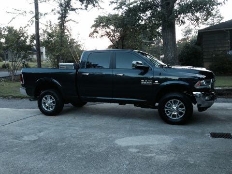1989 Ford Bronco - This black Ram pickup truck is parked on a concrete driveway with trees and a house in the background.