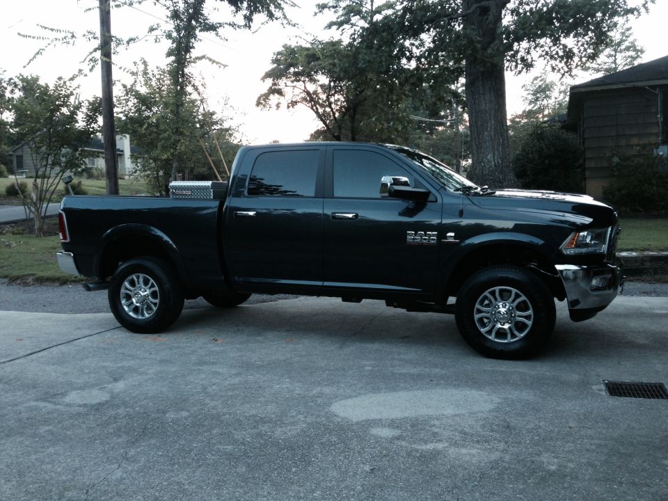 Black Ram pickup truck parked on a driveway, side view. Toolbox in the bed