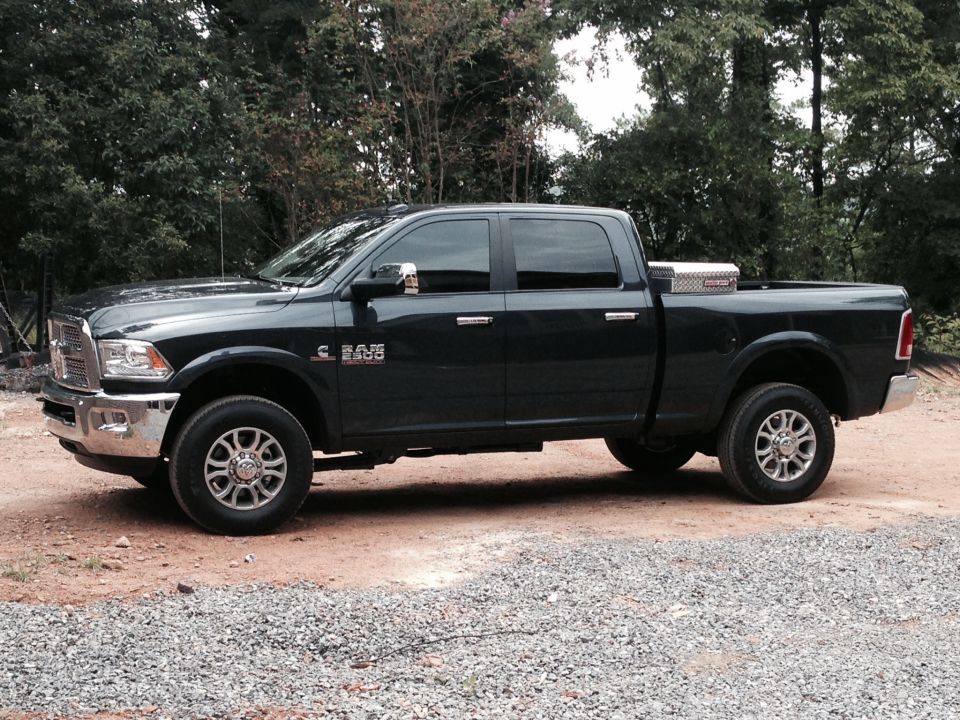 Dark colored Ram pickup truck with a toolbox in the bed, parked on gravel