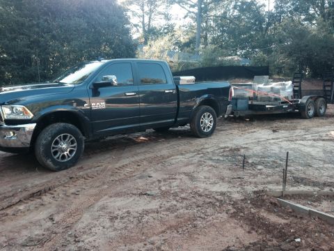 1989 Ford Bronco - Ram 2500 pickup truck is seen towing a trailer loaded with materials on a construction site.