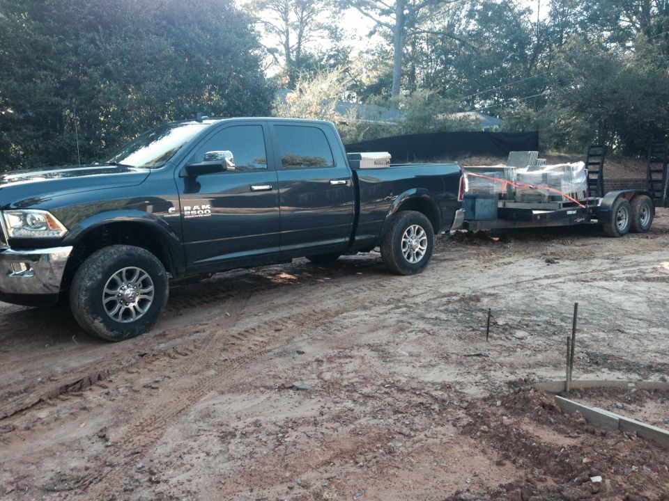 Dark blue Ram 2500 pickup truck towing a dual-axle trailer with construction materials