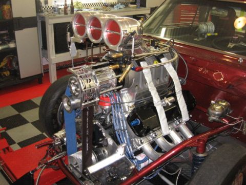 1965 Ford Fairlane - A highly modified engine with a prominent triple carburetor setup is shown in a workshop setting.