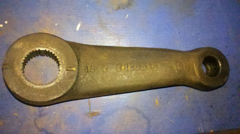 1982 Ford Bronco - A cast iron steering arm with visible part numbers is shown against a blue surface.