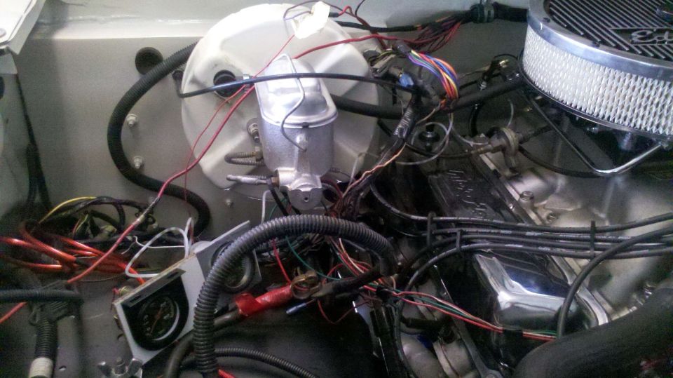 Engine bay with brake booster, master cylinder, air filter, and tangled wiring