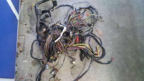 1982 Ford Bronco - A complex wiring harness lies on the ground, its many wires a tangled mess.