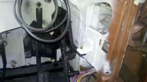 1982 Ford Bronco - The interior firewall and pedal assembly of a vehicle are shown, with exposed wiring and some rust.
