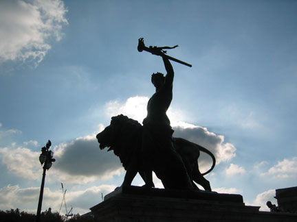 1996 Ford Crown Victoria - A silhouette of a statue depicting a person on a lion, set against a bright, cloudy sky.