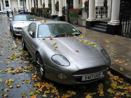 1996 Ford Crown Victoria - A silver Aston Martin DB7 is parked on a street with fallen leaves scattered around it.