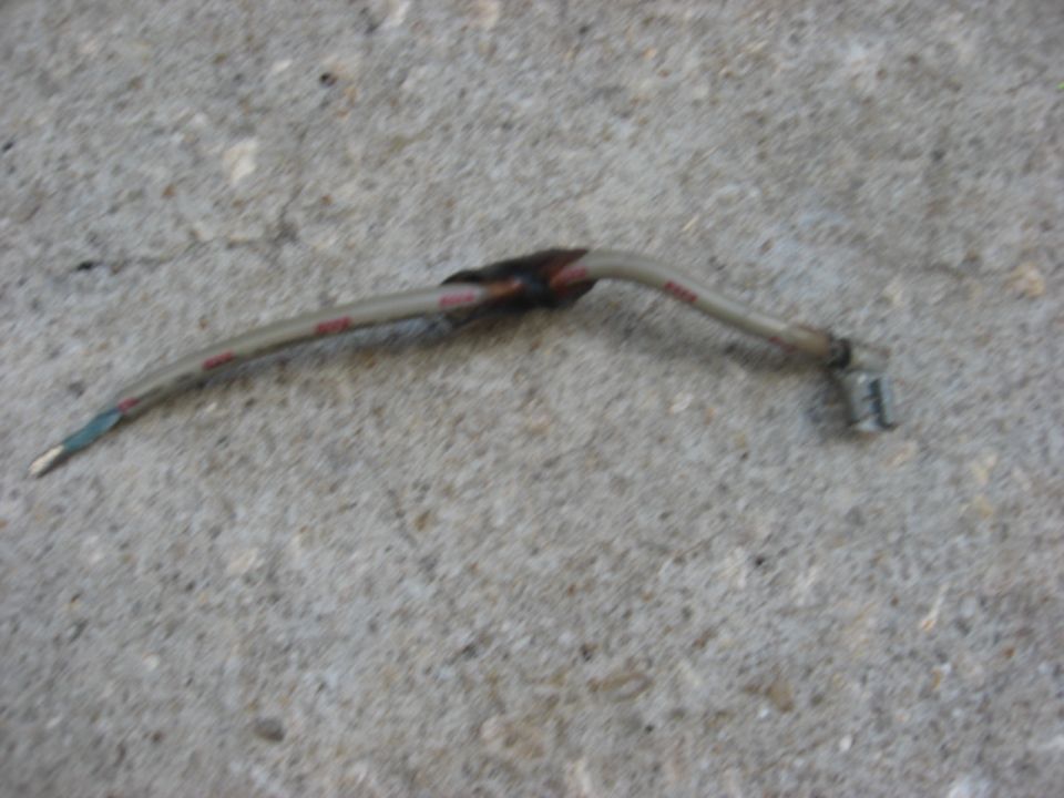 Bent metal wire harness with black electrical tape and red markings