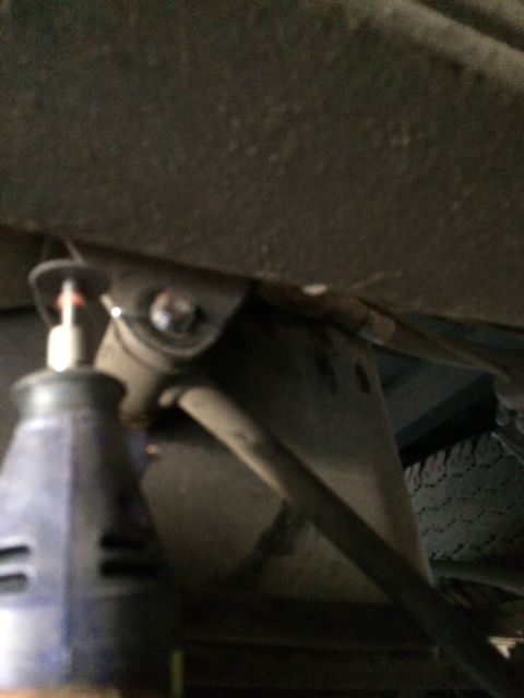 1997 Dodge 3500 - A rotary tool is used on a vehicle's sway bar mounting bracket, with a tire visible in the background.