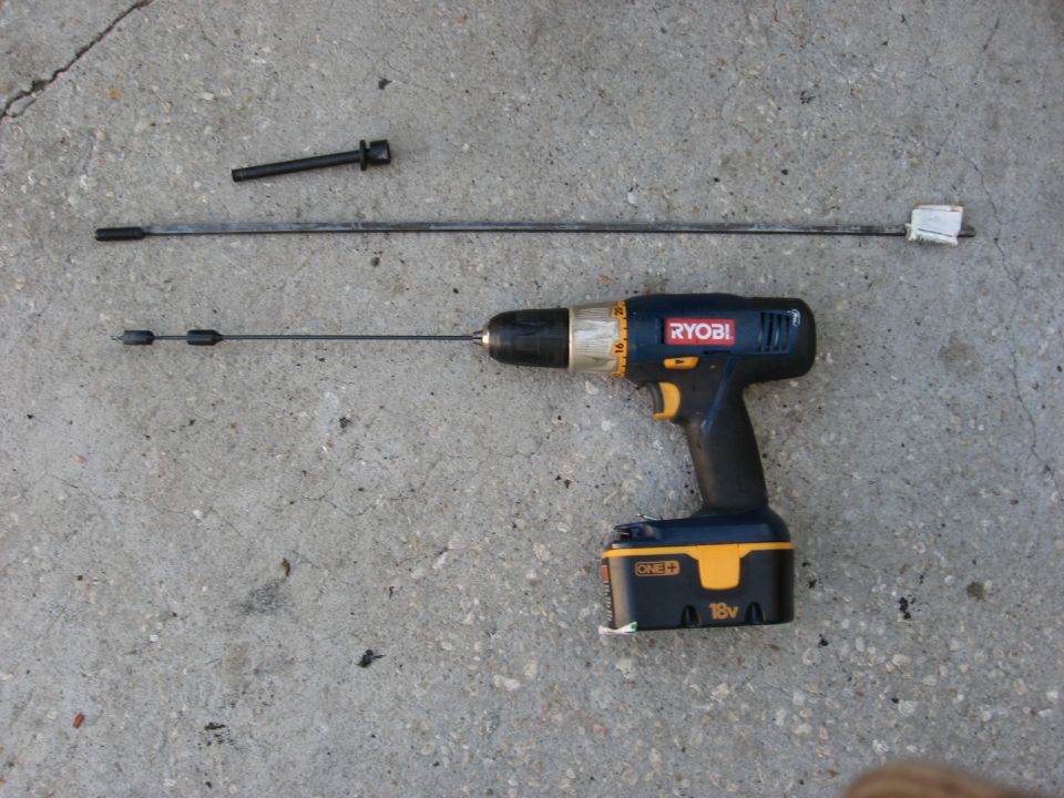 Ryobi 18V drill with two automotive cables and a bolt on concrete