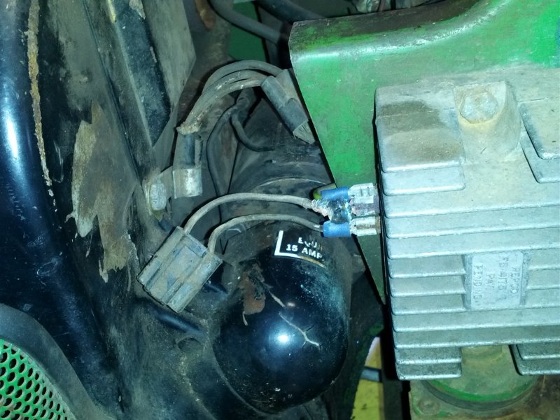 Close-up of a black cylindrical part labeled '15 AMP' and a silver finned regulator with wires connected