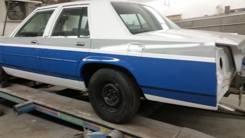 1991 Ford LTD Crown Victoria - This sedan is on a lift with its rear quarter panel missing, revealing its internal structure.