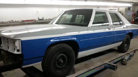 1991 Ford LTD Crown Victoria - This Ford sedan is in a repair shop, showing its two-tone paint job and missing front bumper.
