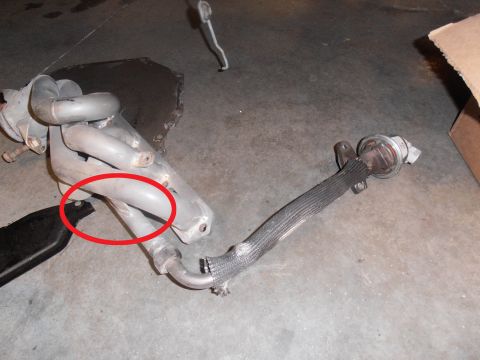 1990 Ford Bronco - A collection of exhaust system parts lies on a concrete floor.