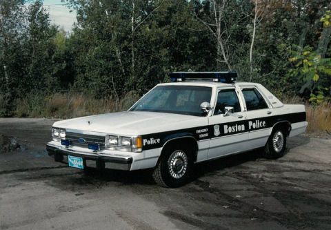 1991 Ford LTD Crown Victoria - A 1991 Ford Crown Victoria LTD police car is seen from a 3/4 front view, marked with "Boston Police" and emergency lights.