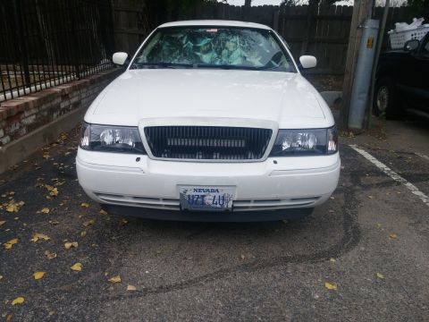 2000 Mercury Grand Marquis - The front end of a white 2000 Mercury Grand Marquis is shown parked on asphalt with fallen leaves.