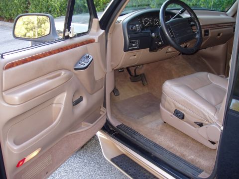1996 Ford Bronco - The interior of a beige and tan SUV is shown, the driver's seat, dashboard, and door panel.