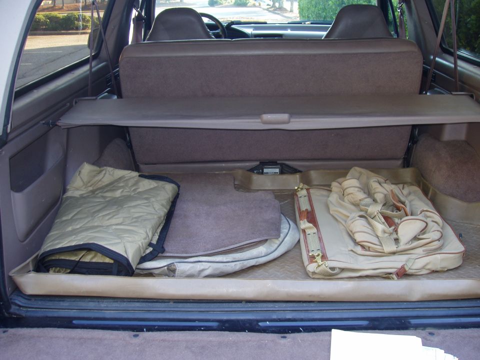 Cargo area of SUV with folded blankets and a bag. Seats and steering wheel visible