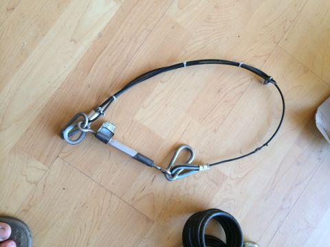 2003 Honda CR-V - A tow bar safety cable with metal connectors lies on a wooden floor.