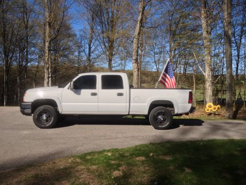 2006 Chevrolet Silverado 2500 - A white pickup truck is parked on a paved surface with trees in the background.