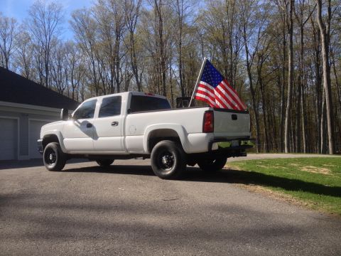 2006 Chevrolet Silverado 2500 - A white pickup truck is parked on a driveway with trees in the background.