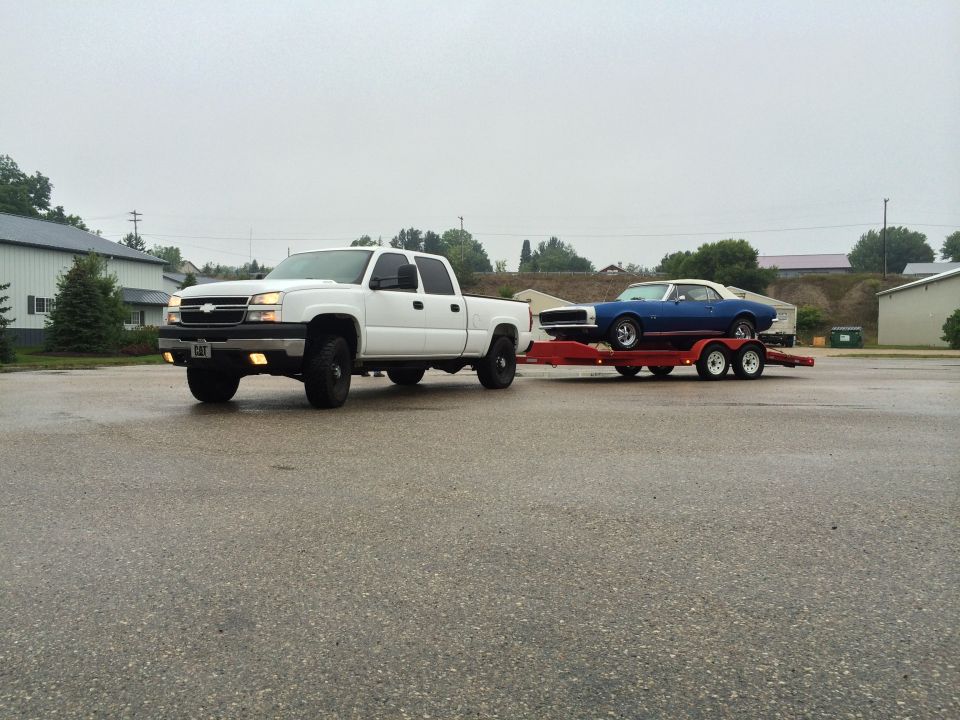 White pickup truck towing a blue classic car on a trailer