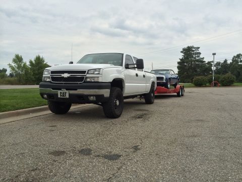 2006 Chevrolet Silverado 2500 - 2006 Chevrolet Silverado 2500 towing a blue classic car on a trailer.