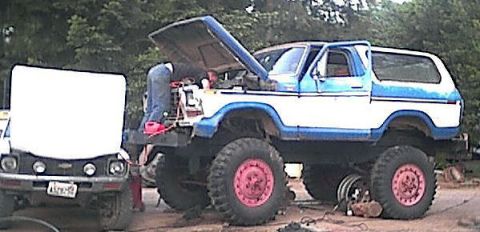1978 Ford Bronco - A lifted blue and white 1978 Ford Bronco is being worked on with its hood open, parked next to another vehicle.