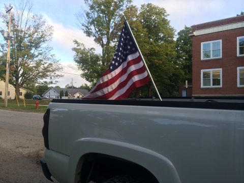 2006 Chevrolet Silverado 2500 - A white 2006 Chevrolet Silverado 2500 is seen from the rear quarter panel, flying an American flag.